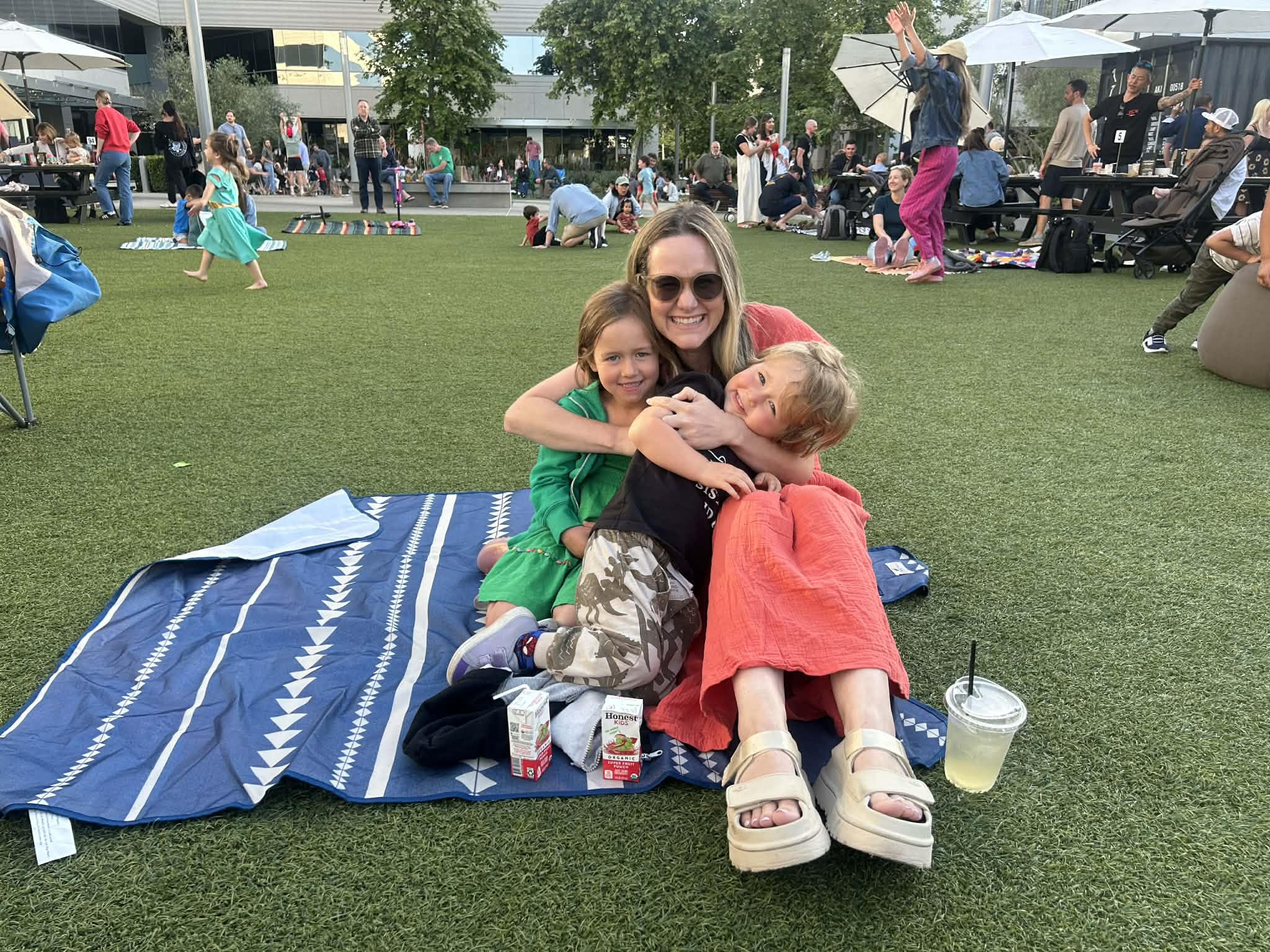 Mom snuggling with kids at the park — the surprising connection between motherhood and clear skin