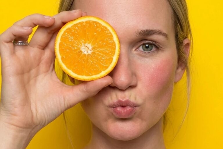 Brittany holding an orange while explaining vitamin C for acne-prone skin